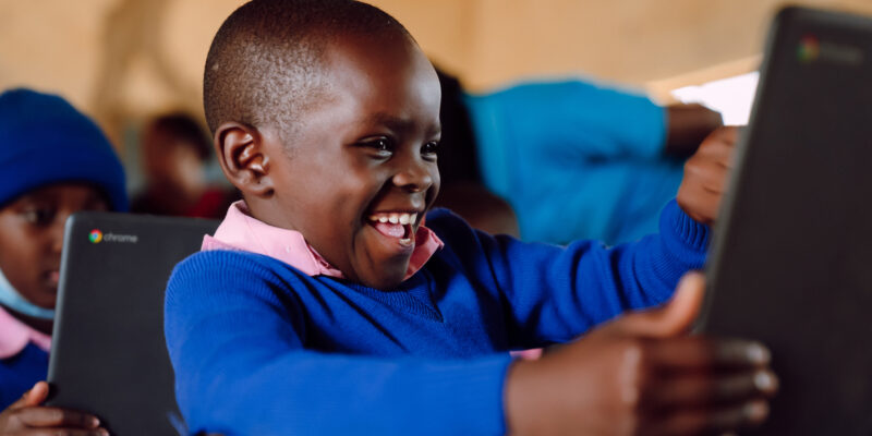 A Kenyan child smiles at a computer.