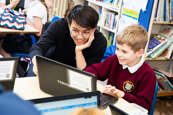 A teacher helps a student with a computing task