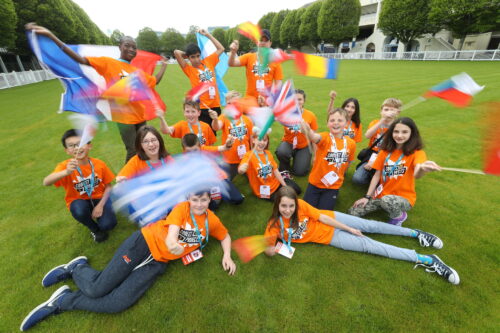 A group of Coolest Projects participants from all over the world wave their flags.