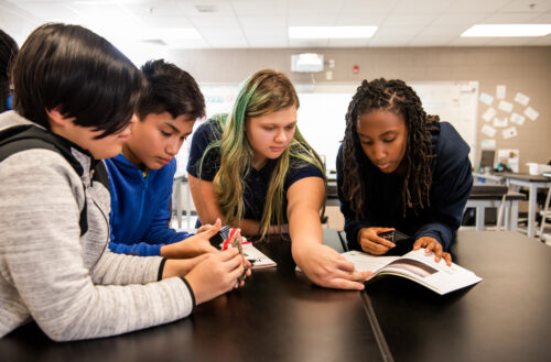 A group of young people investigate computer hardware together.