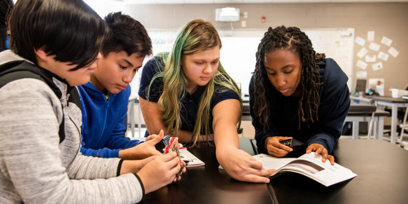 A group of young people investigate computer hardware together.