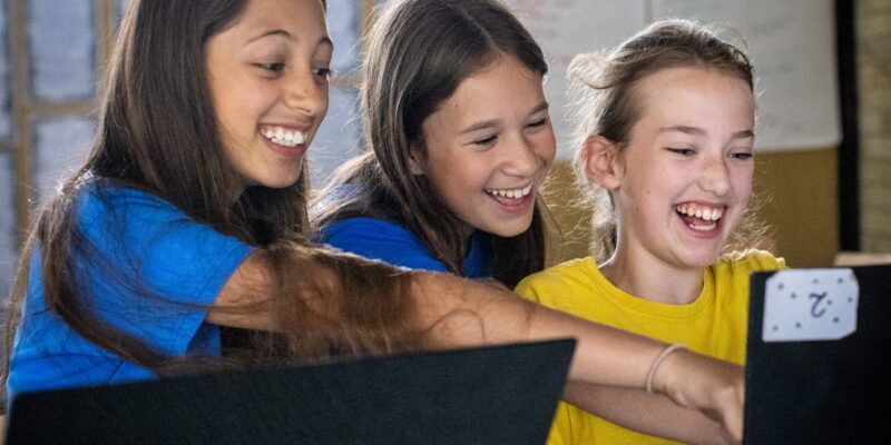 Three learners laughing at a laptop in a Code Club.