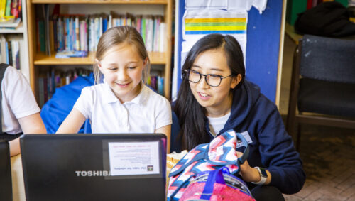 Woman computing teacher and young female student at a laptop.