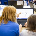 Woman teacher and female student at a laptop.