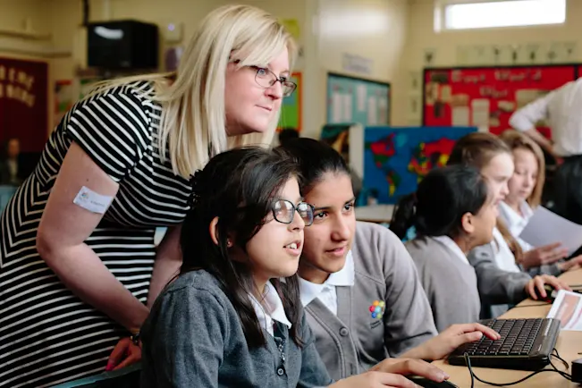 Teacher and two learners in a computing lesson.