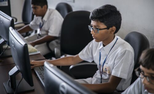 Photo of a young person coding on a desktop computer.