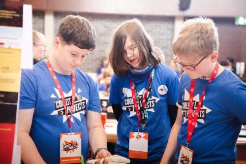 Photo of three young creators discussing their project at an in-person Coolest Projects event.