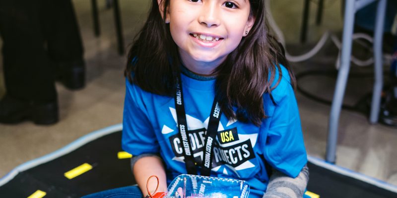 A smiling girl holding a robot buggy in her lap