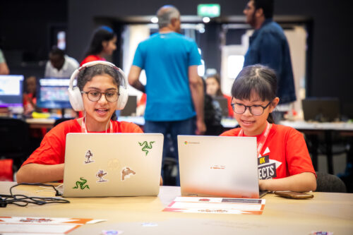 Photo of two young people sitting at laptops at a Coolest Projects event.