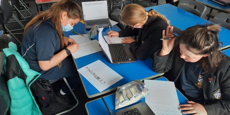 Girls do a cybersecurity activity at a school club.