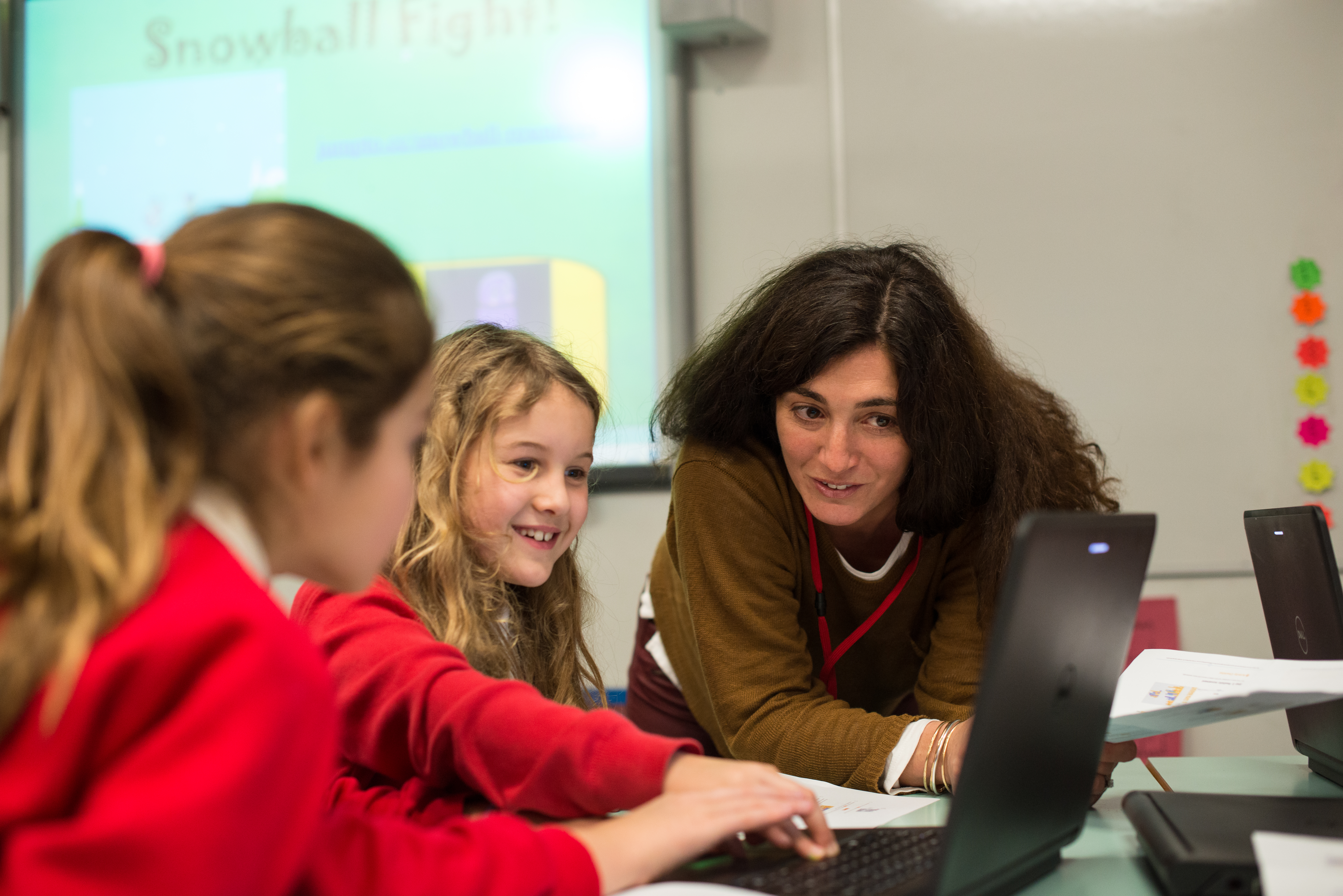 A teacher aids children in the classroom