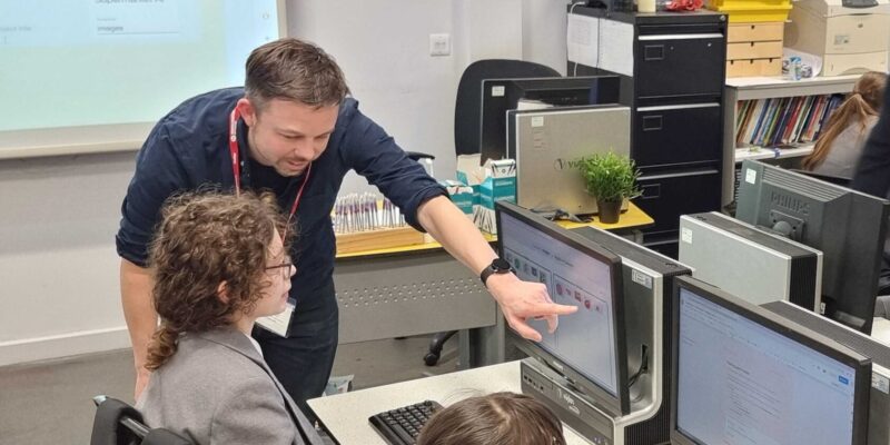 An educator points to an image on a student's computer screen.