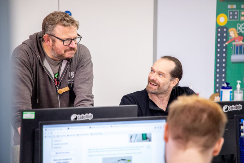 Two adults learn about computing at desktop computers.