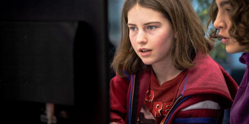 Close up of two young people working at a computer.