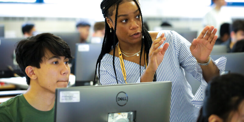 A teacher explains something to a learner in a computer science class.