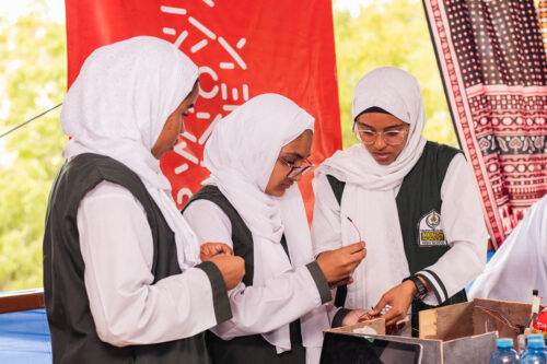 Three young people working on a computing project.