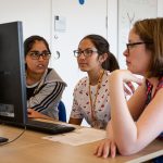 Woman teacher and female students at a computer