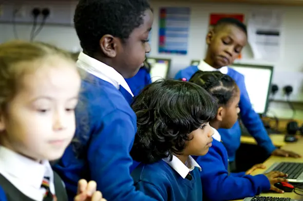 Learners at computers in a primary school classroom.