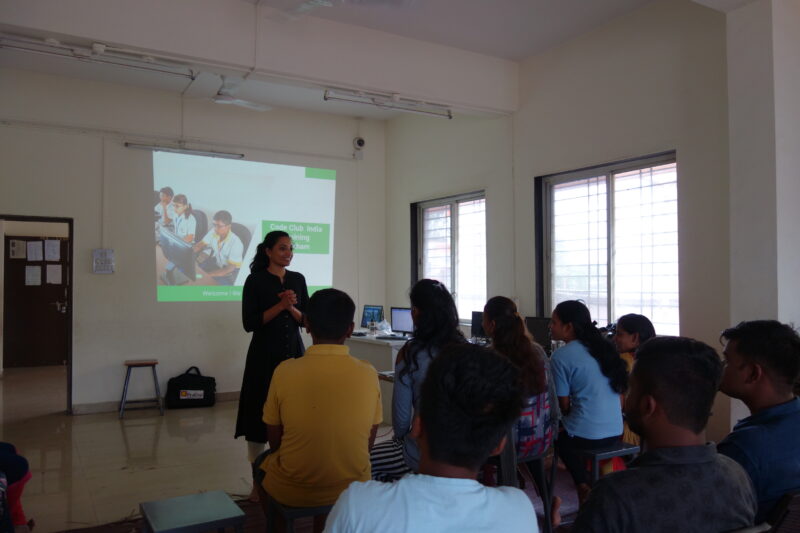 In a classroom, a group of people watch the speaker at the front give a presentation.