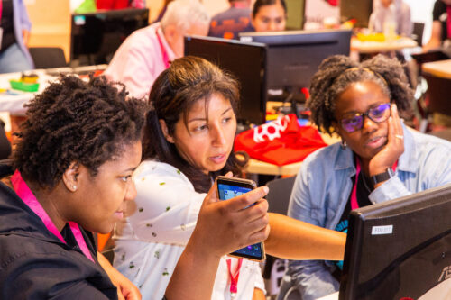 Three computer science educators discuss something at a screen.