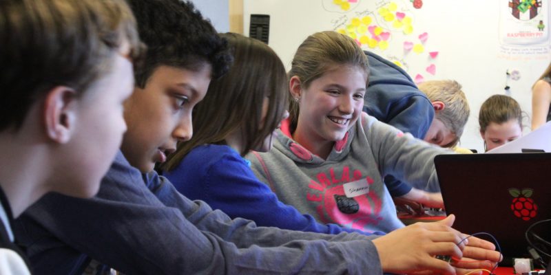 Smiling learners in a computing classroom.