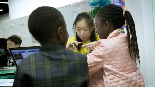 Yang mentors two young learners during a CoderDojo session.