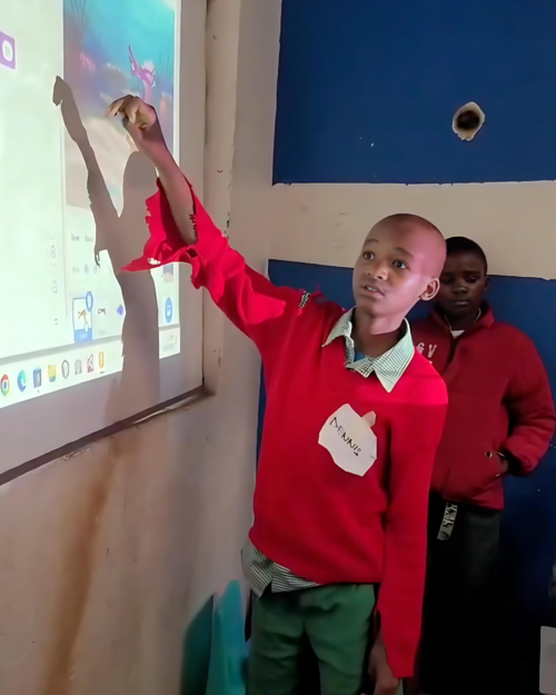 A young person shows off their Scratch code projected onto a wall.