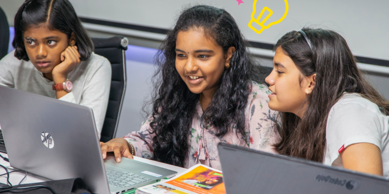 Three young tech creators at laptops at a Code Club session.