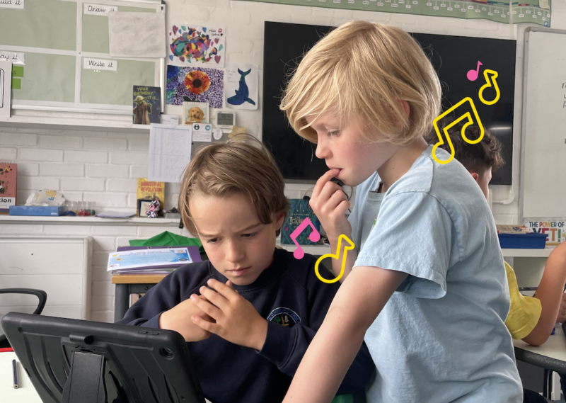 Two young tech creators at a tablet at a Code Club session.