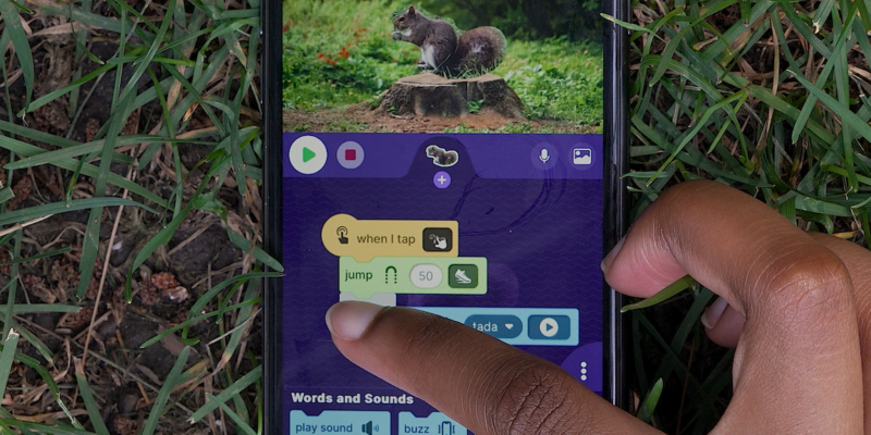 A young person connects coding blocks in their OctoStudio phone app.